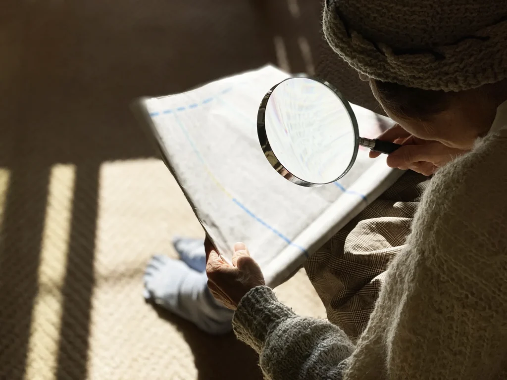 虫眼鏡で新聞を読む一人暮らしの高齢者女性